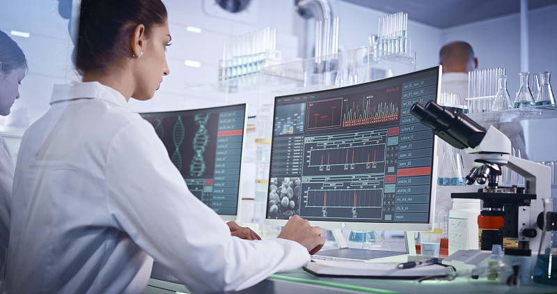 研究DNA突变的研究小组。前景中有DNA螺旋结构的计算机屏幕图片下载